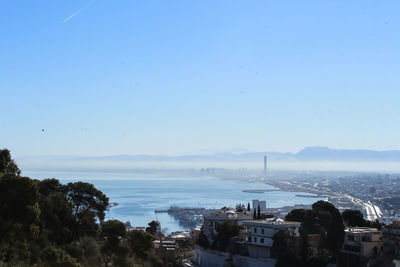 High angle view of city by sea against clear sky