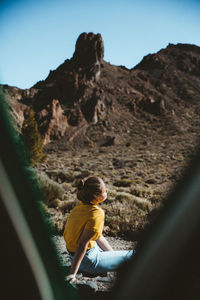 Side view of man sitting on rock