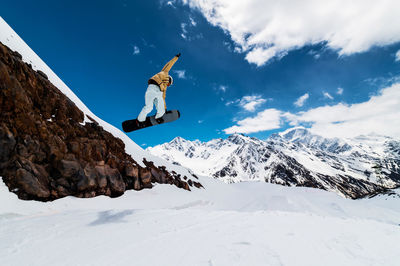 Low angle view of man skiing on snowcapped mountain against sky