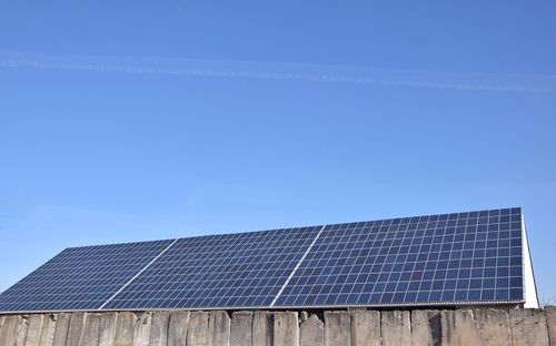 Low angle view of solar panels against clear blue sky