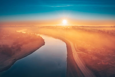 Aerial view of river flowing on landscape during sunrise