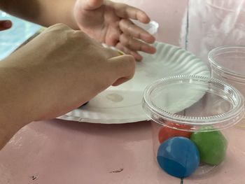 High angle view of baby hand holding glass on table