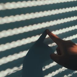 Cropped hand touching railing shadow on wall