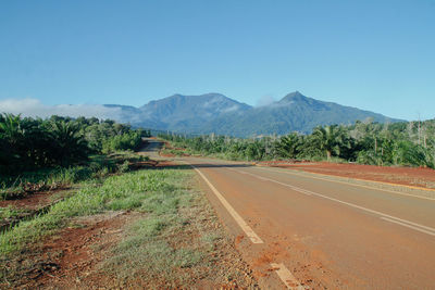 Road leading towards mountains against sky