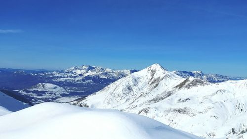 Scenic view of snowcapped mountains against blue sky