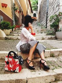 Full length of fashionable woman sitting on steps in town