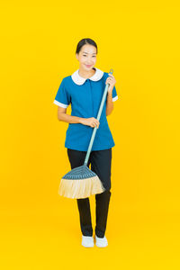 Portrait of smiling young woman standing against yellow background