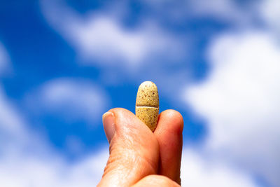 Close-up of person holding hand against sky