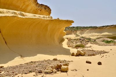 Rock formations on shore against sky