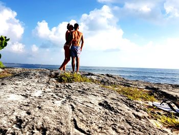 Full length of couple standing at beach against sky