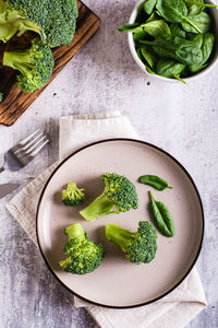 Fresh broccoli and spinach leaves on a plate on the table. healthy food, green food