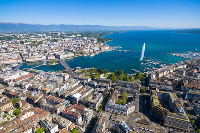 Aerial view of cityscape and sea against blue sky