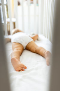 Low section of woman lying on bed at home