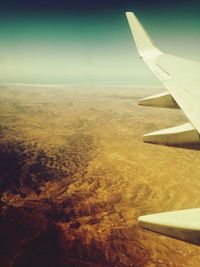 Cropped image of airplane wing over landscape