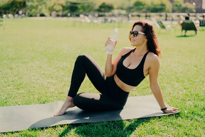 Woman wearing sunglasses sitting on mat in park