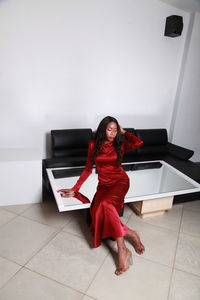 Fashionable woman sitting on mirror table at home