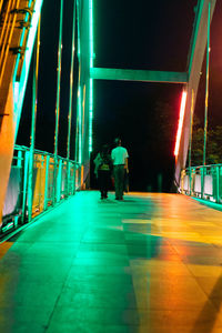 Rear view of people walking on illuminated corridor