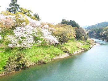 Scenic view of river by mountains against sky