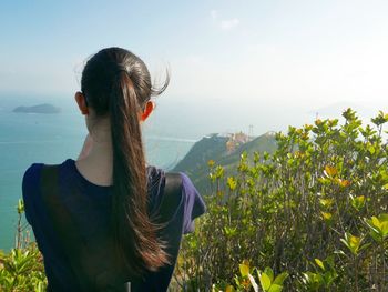 Rear view of woman looking at mountains against sky