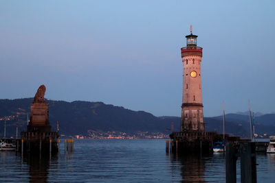 Lighthouse by sea against clear sky