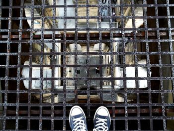 Low section of person standing on metal grate