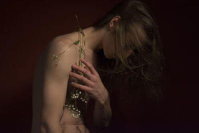 Shirtless man with flowers against black background