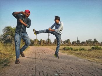 Full length of friends standing on landscape against clear sky