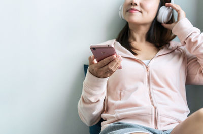 Young woman using phone against white background