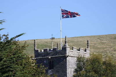 Flag by building against clear blue sky