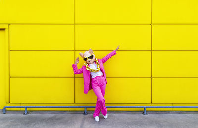 Full length of a girl standing against yellow wall