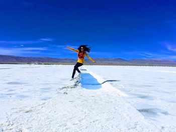 Full length of woman jumping on salt flat