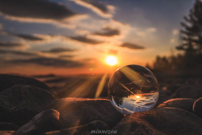 Close-up of illuminated light bulb against sky during sunset