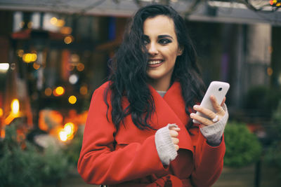 Portrait of smiling young woman using mobile phone at night