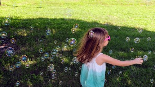 Girl standing amidst bubbles at park