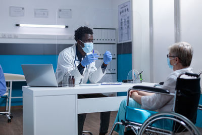 Doctor discussing with disabled patient at clinic