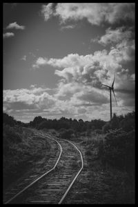 Railroad tracks by road against sky