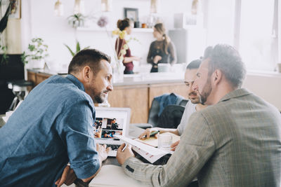 Creative male entrepreneurs discussing at table in office