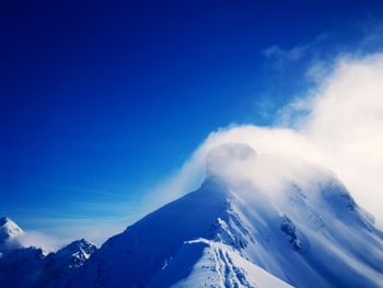 Scenic view of snowcapped mountains against blue sky