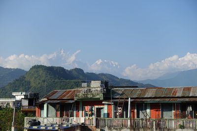 Houses by mountain against sky