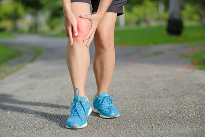 Low section of woman suffering from pain on road