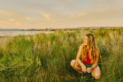 Young woman sitting in tall grass by mono lake in northern california.