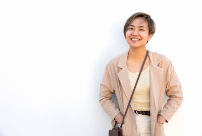 Portrait of young woman standing against white background