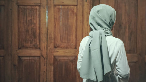 Rear view of person standing against wooden wall