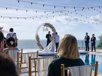 Rear view of people sitting on chair against sky