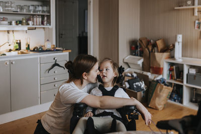 Mother taking care of disabled child in wheelchair at home