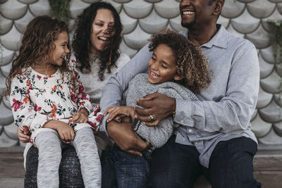 Lifestyle image of happy family tickling each other and laughing while