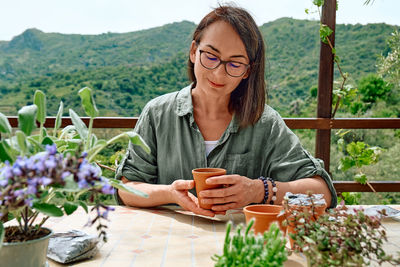 Woman sowing medicinal or aromatic herbs in clay pot on balcony. home planting and food growing.
