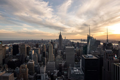 Aerial view of buildings in city against cloudy sky