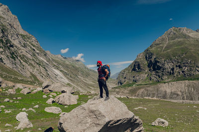 Rear view of man walking on mountain against sky