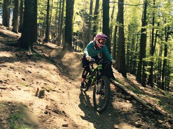 People riding bicycle on dirt road in forest